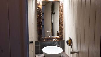 A bathroom with a wooden vanity, a white sink, and a mirror with a wooden frame.