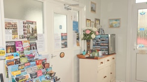 A reception area with a bulletin board displaying various travel brochures and a television on a cabinet. - The Clydesdale (Paignton)