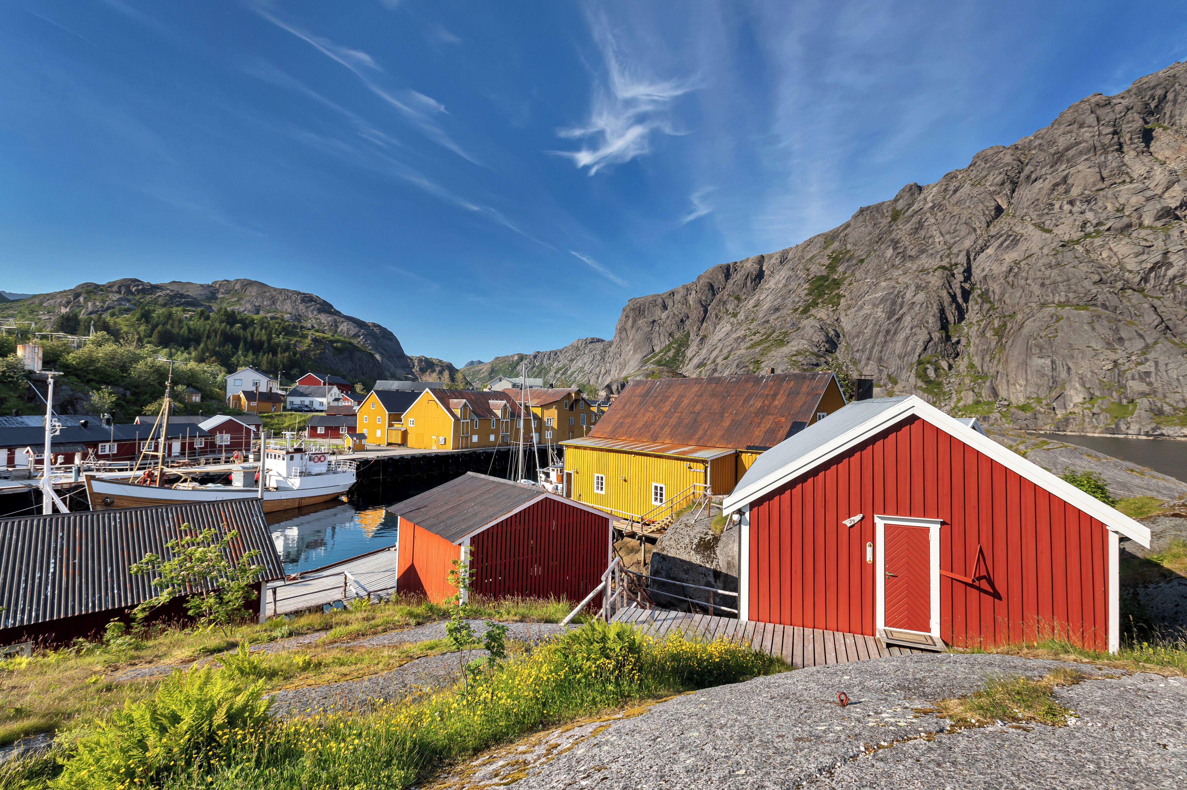 A coastal village with colorful buildings, a dock, and a mountain backdrop.