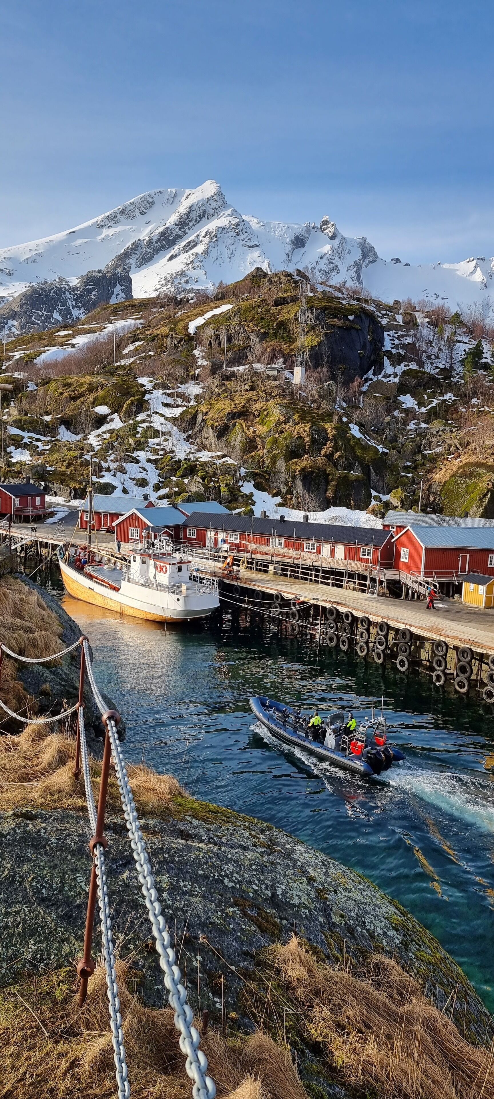 Un pueblo costero con un muelle, un barco y montañas al fondo.