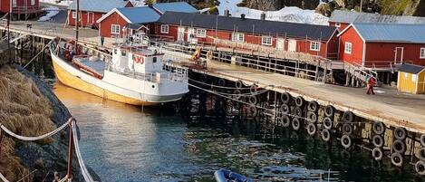 Un pueblo costero con un muelle, un barco y montañas al fondo.