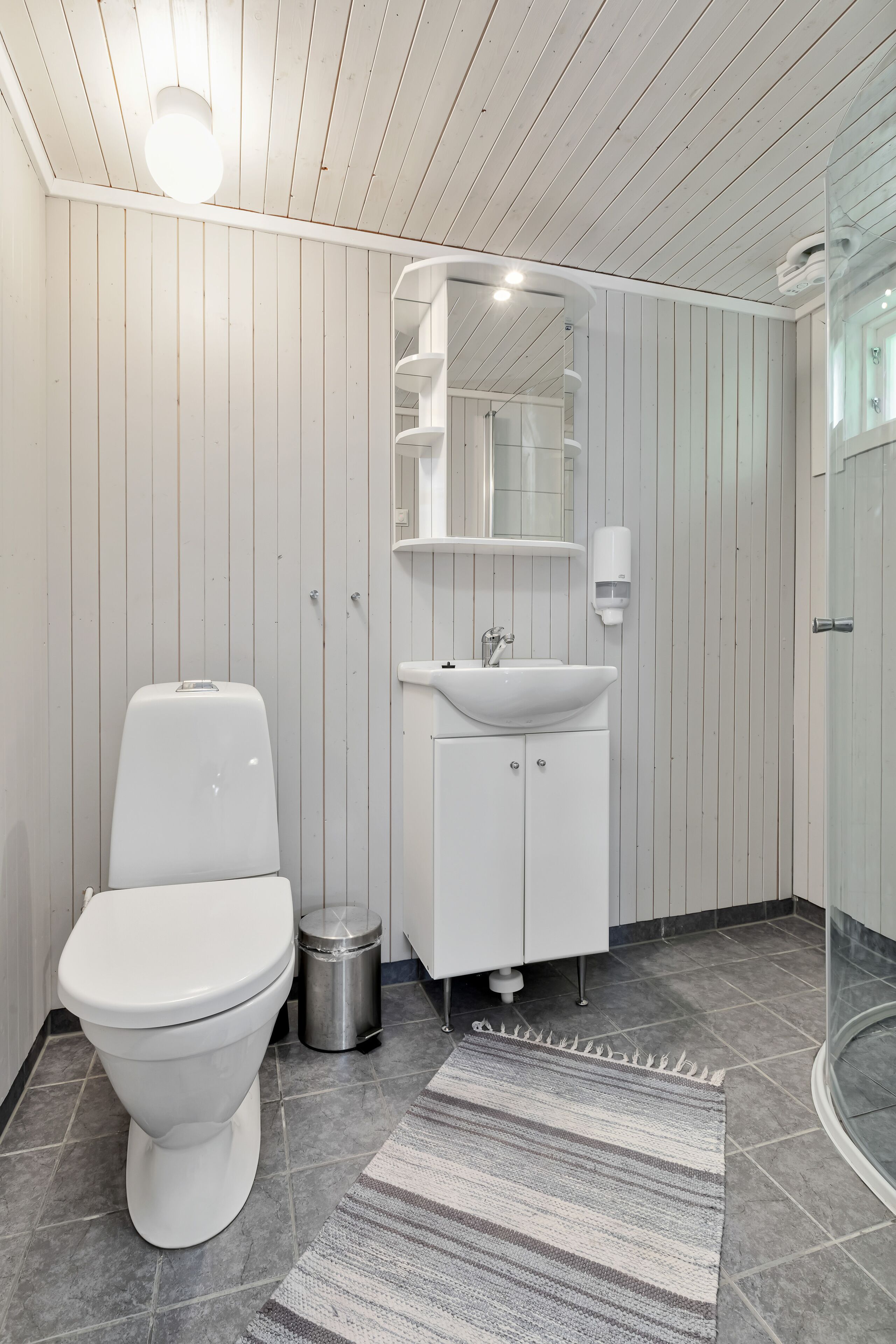 A modern bathroom with a white toilet, a sink with a mirror above it, and a shower area.