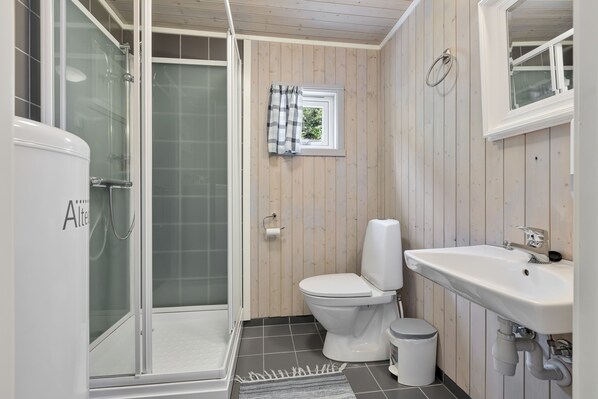 Un baño con ducha de vidrio, inodoro y lavamanos.