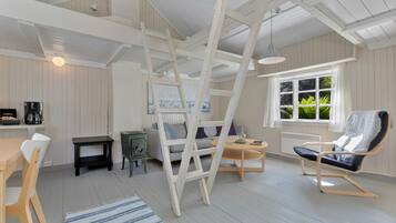 A room with a wooden ladder, a sofa, a table, and a chair.