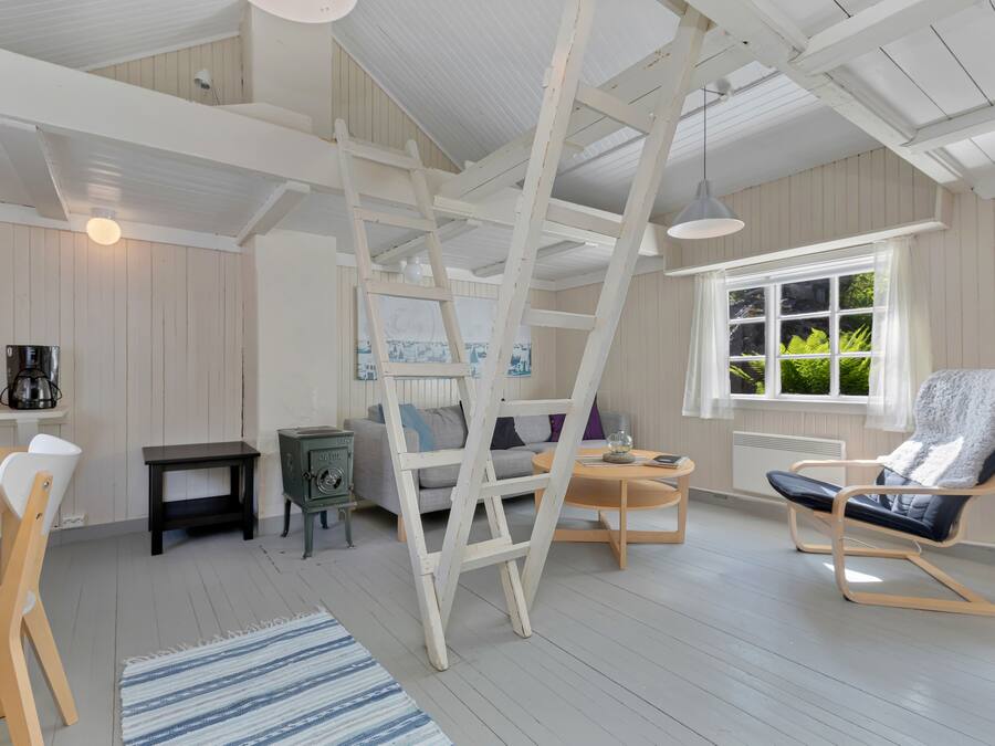 A room with a wooden ladder, a sofa, a table, and a chair.
