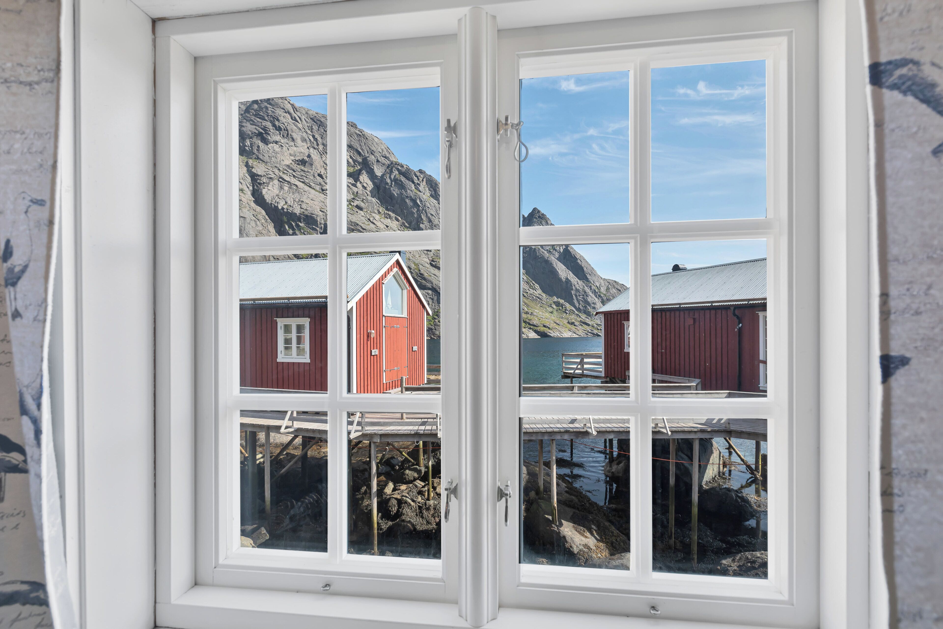 Ein Fenster mit Blick auf ein rotes Gebäude und einen Berg.