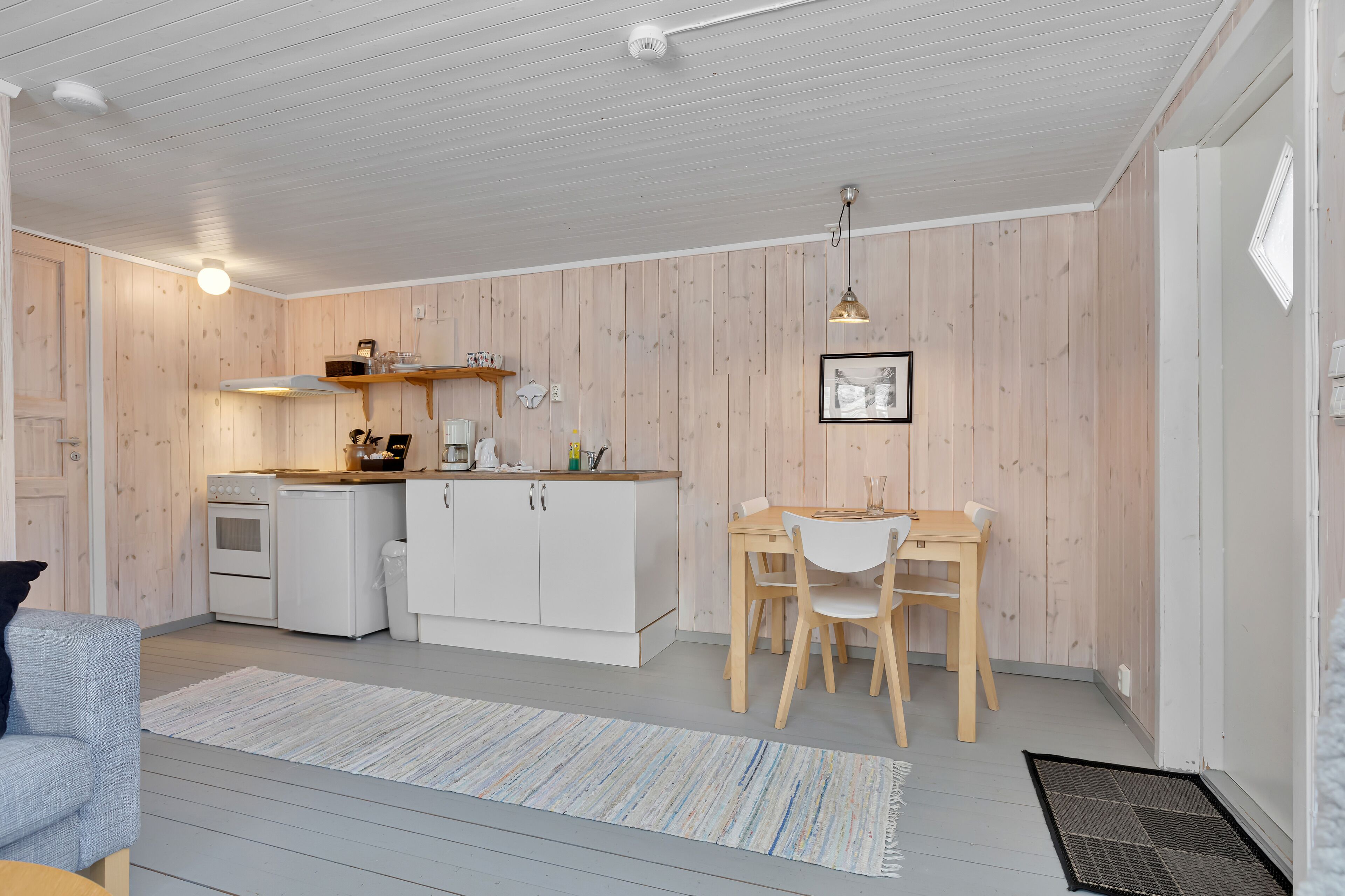 A compact kitchen with white cabinets, a wooden countertop, and a dining area with a table and chairs.