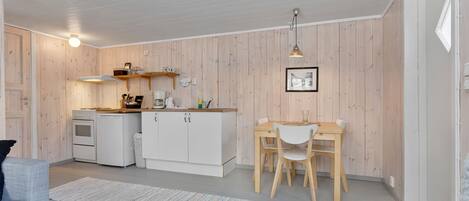 A compact kitchen with white cabinets, a wooden countertop, and a dining area with a table and chairs.