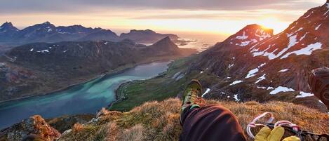 Une personne assise sur une montagne, avec une vue sur un lac et d’autres montagnes en arrière-plan.