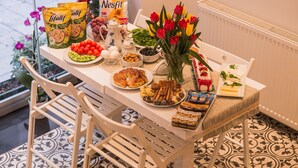 Une table à manger avec différents plats, un vase de tulipes et un radiateur.