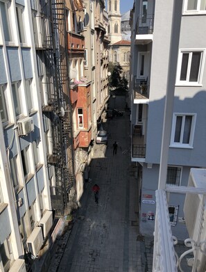 A narrow street with buildings on either side, featuring balconies and air conditioning units. - The House of Tulpan (Istanbul)