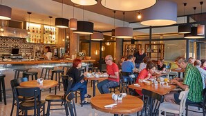 Un restaurante moderno con mesas redondas, sillas negras e iluminación colgante.