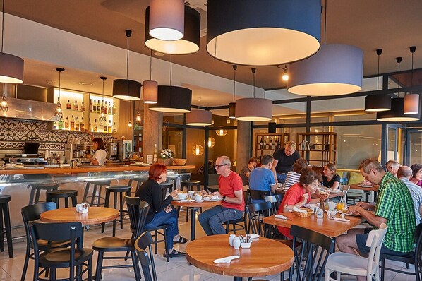 A modern restaurant with round tables, black chairs, and pendant lighting. - Hotel Benahoare (Los Llanos de Aridane)
