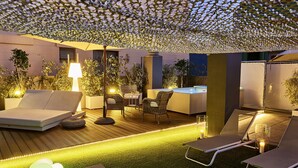 Un espacio de descanso al aire libre con sillones, una mesa y un jacuzzi.