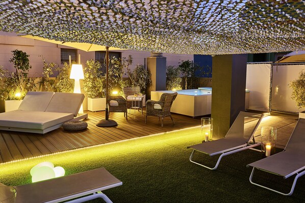 Un espacio de descanso al aire libre con sillones, una mesa y un jacuzzi.