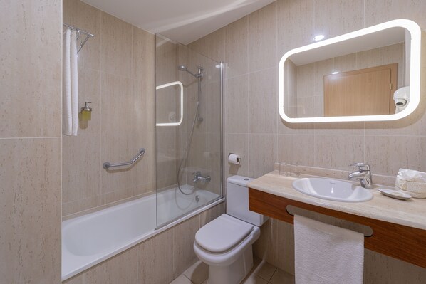 Un baño moderno con ducha de vidrio, inodoro blanco y tocador con espejo.