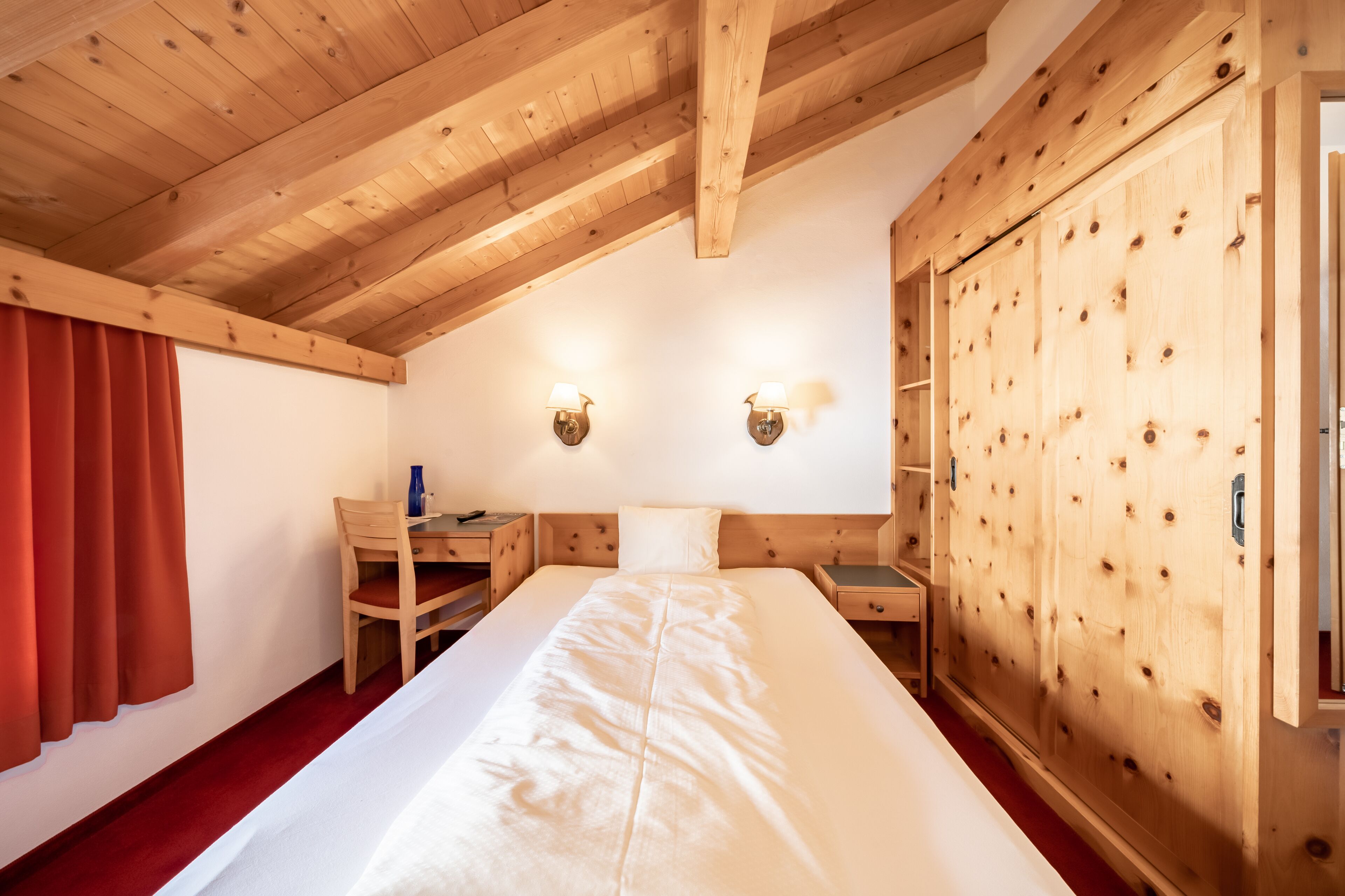 Une chambre à coucher en bois, avec un lit, un bureau et une armoire.