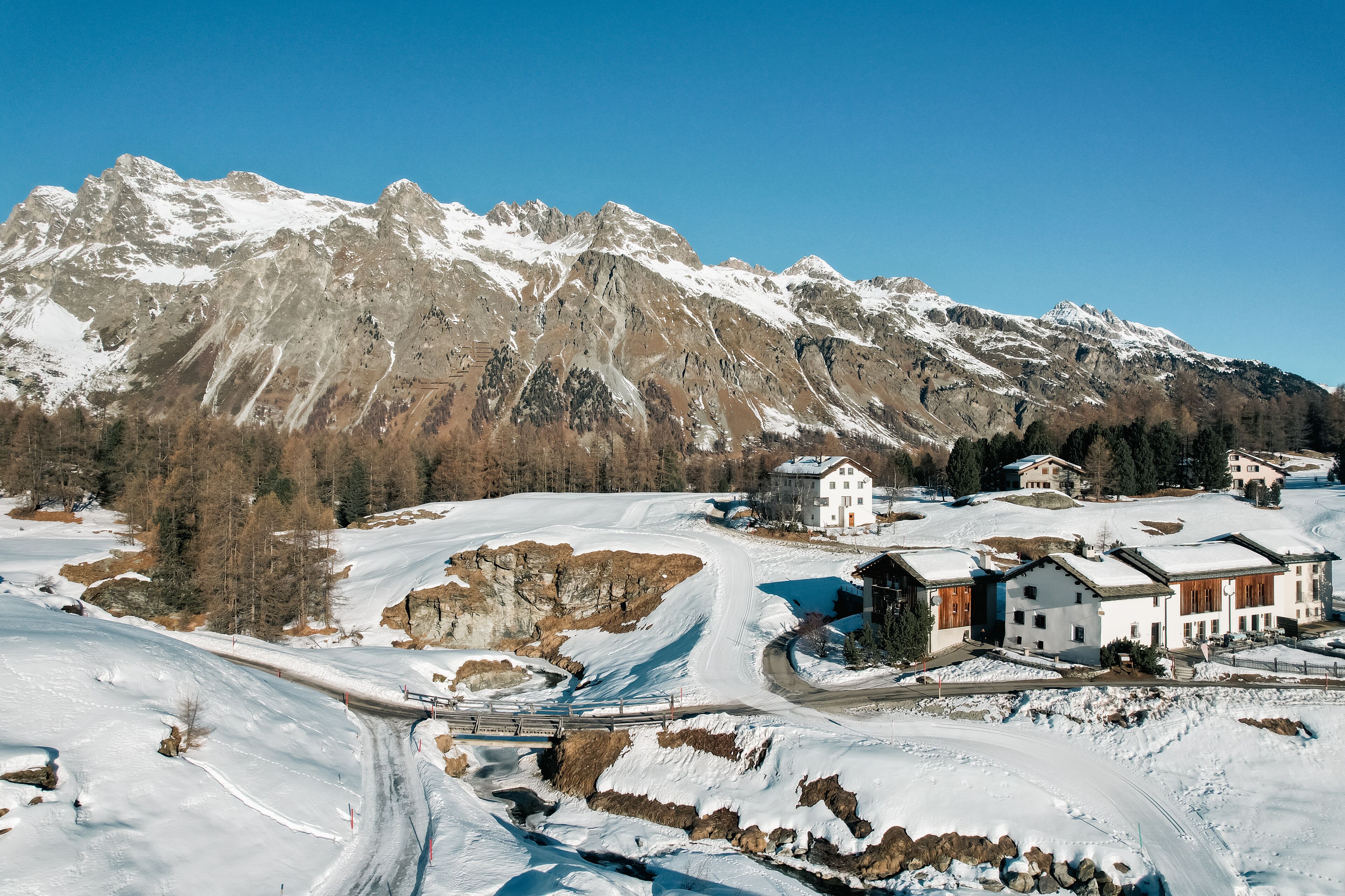Paesaggio montano innevato con un piccolo villaggio e case.