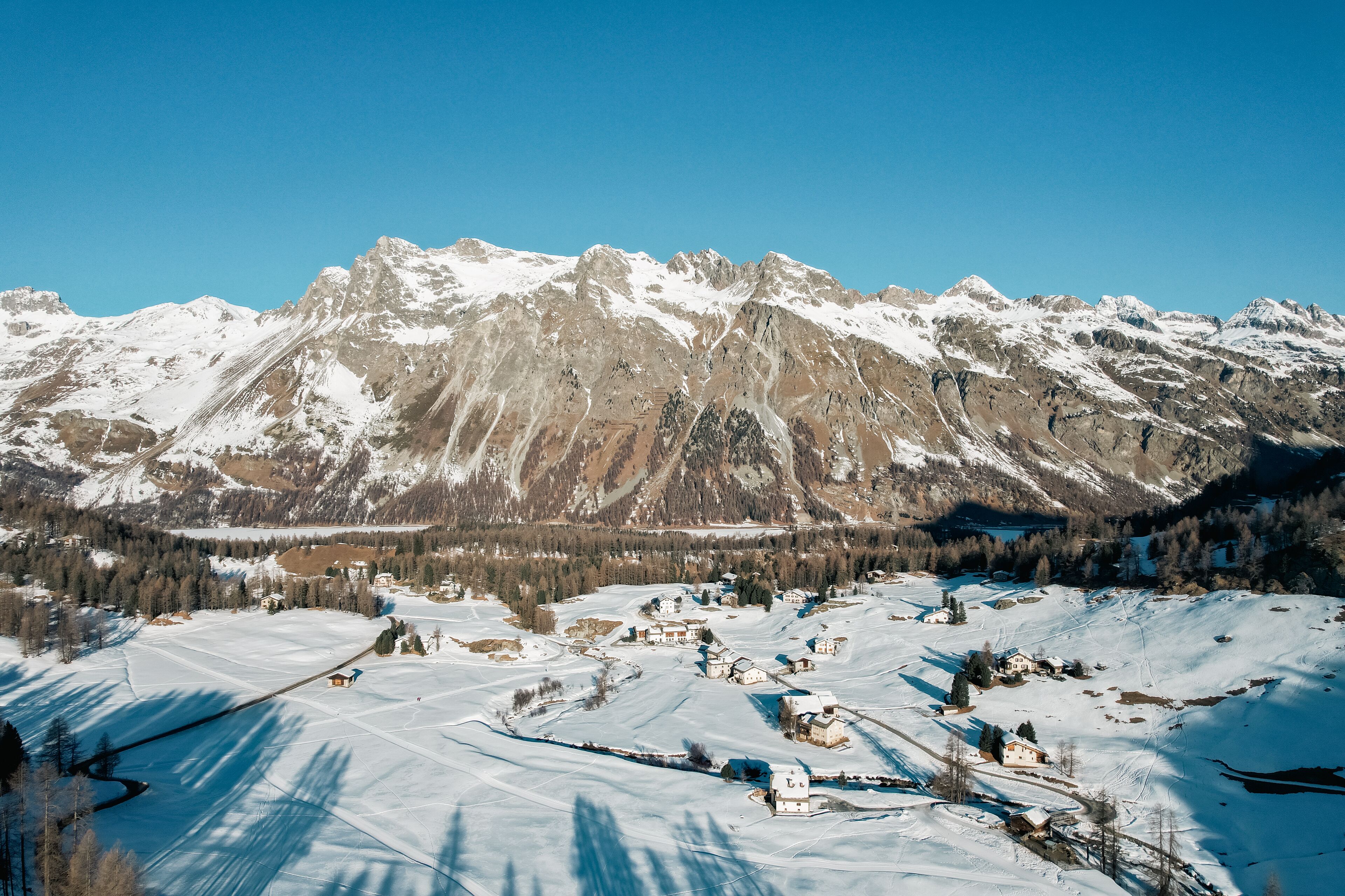 A snow-covered mountainous landscape with a small village and houses.