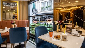 Interior moderno de un hotel con un comedor que presenta sillas azules y una mesa con una taza de café y pasteles.