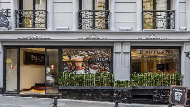 Exterior del Hotel Endican Sultanhmet, con una gran vitrina decorada con motivos de café y un cartel.