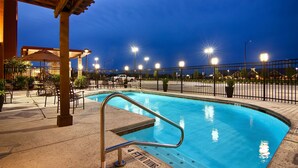 A swimming pool with a 4 FT no diving sign, surrounded by chairs and a covered seating area.