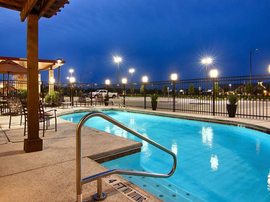 A swimming pool with a 4 FT no diving sign, surrounded by chairs and a covered seating area.