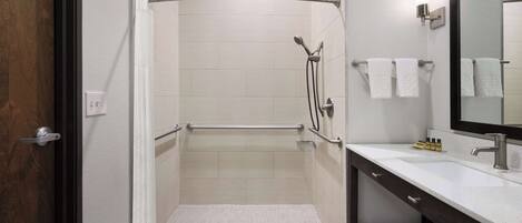 A modern bathroom with a walk-in shower, a vanity with a mirror, and a towel rack.