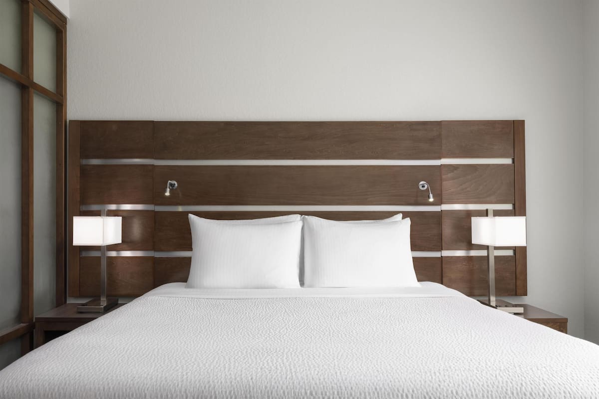 A hotel room with a large bed, two bedside tables, and a wooden headboard.