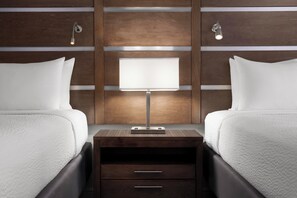 A hotel room with two beds, a nightstand with a lamp, and wooden paneling on the wall. - Best Western Plus College Station Inn & Suites (College Station)