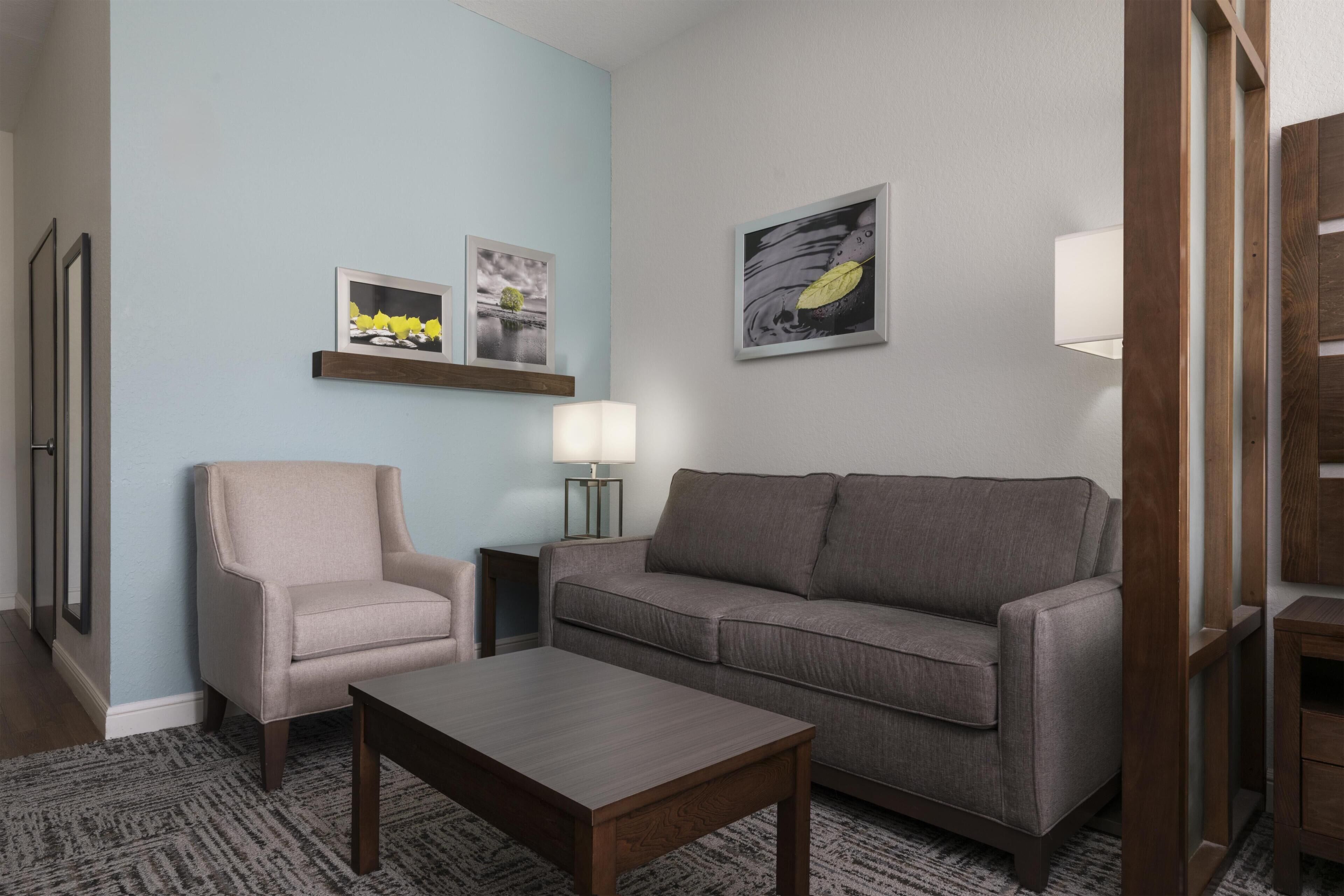 Een woonkamer met een bank, fauteuil, salontafel en een wandlamp.