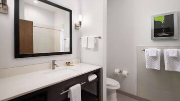A modern bathroom with a large mirror, white sink, and a toilet.
