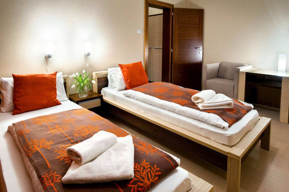A hotel room with two beds, a desk, and a chair.
