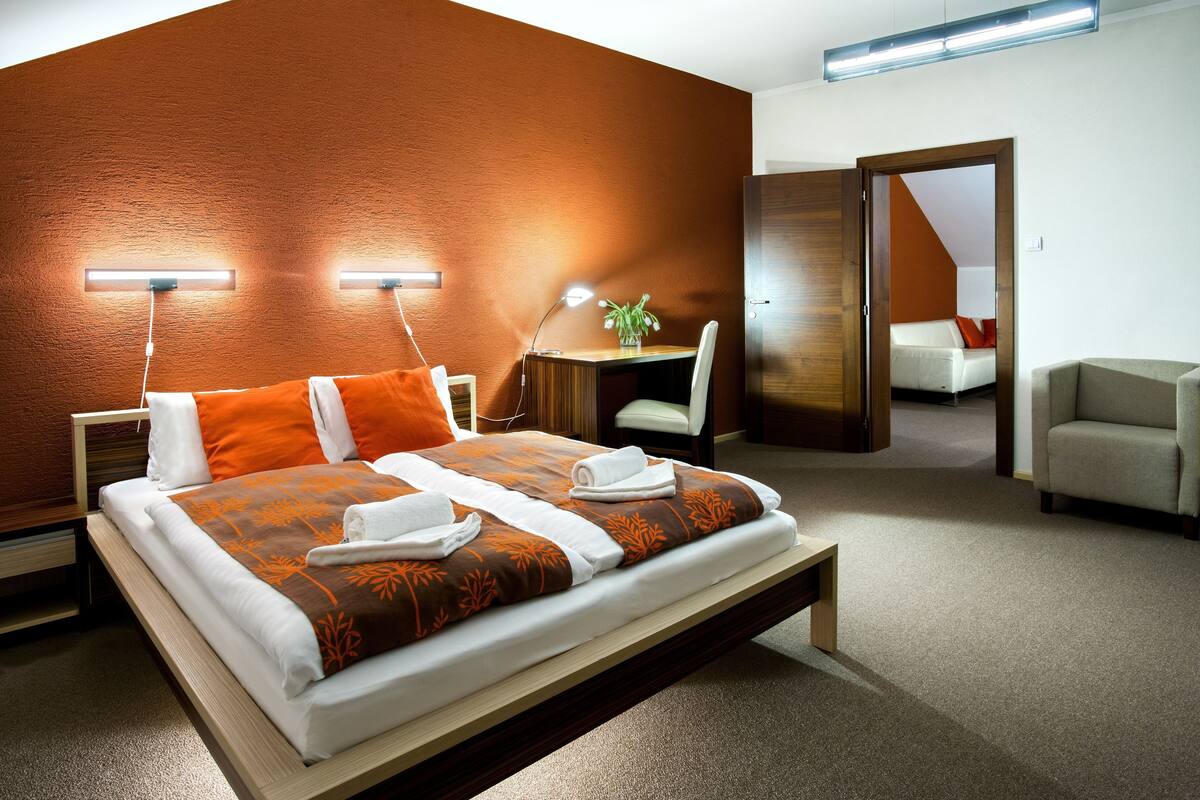 A modern hotel room with a large bed, bedside lamps, a desk, and a chair.