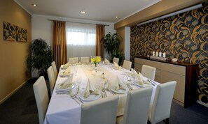 Ein Esszimmer mit einem langen Tisch, gedeckt für eine Mahlzeit, umgeben von Stühlen.