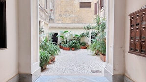 A narrow courtyard with potted plants and a tiled floor. - Dandi Domus (Rome)