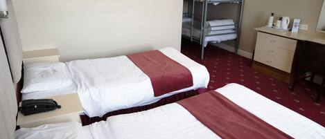 A hotel room with two beds, a desk, a chair, and a television.