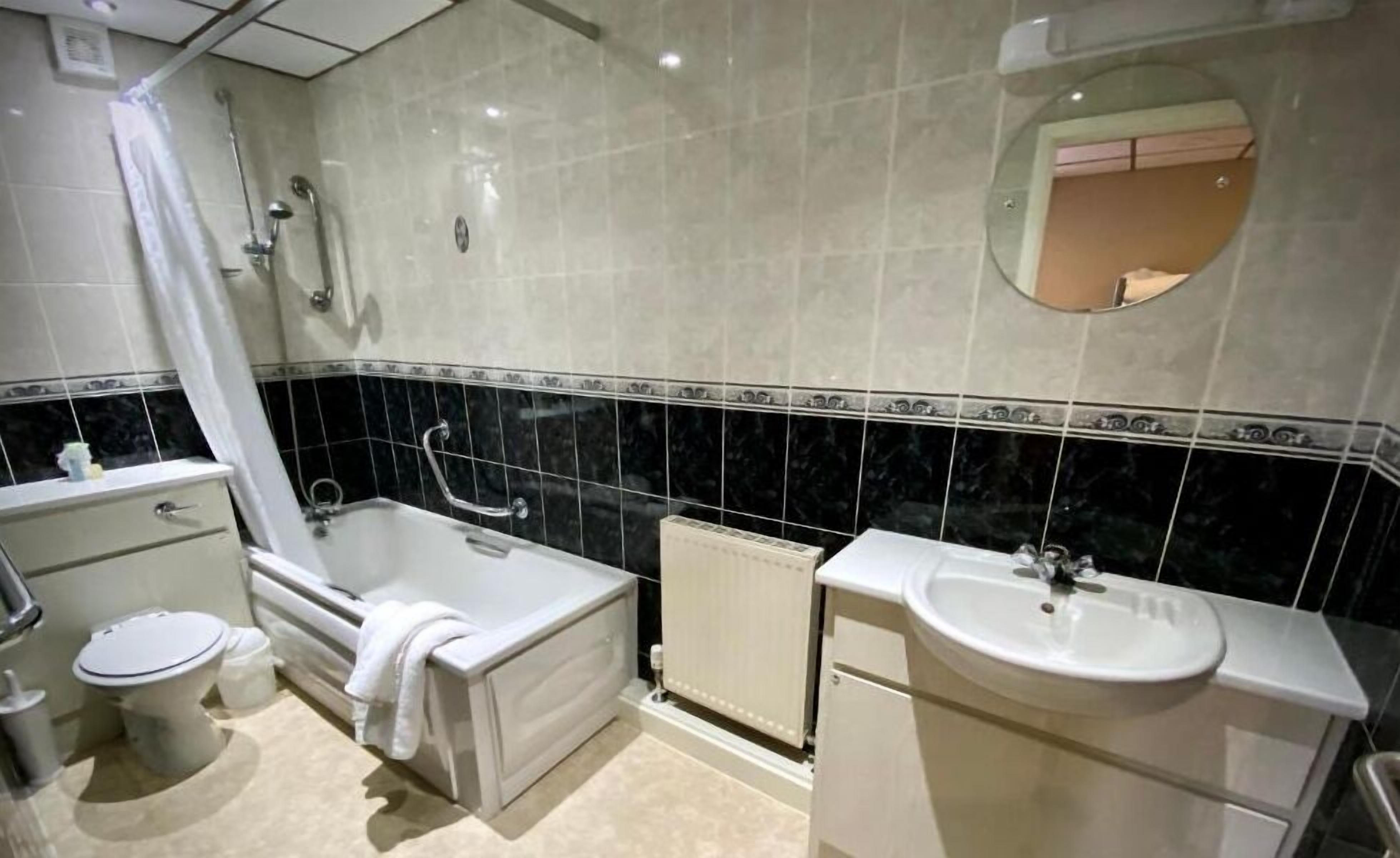 Un bagno con vasca, WC, lavandino e specchio.