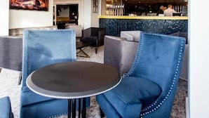 Un área de bar moderna con sillas tapizadas en azul, una mesa redonda y un candelabro.