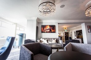 A modern lounge area with a chandelier, comfortable seating, and a large painting of a fire. -  Doric Hotel (Blackpool)