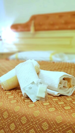 Un lit avec une couvre-lit à motifs et une couverture blanche soigneusement pliée.