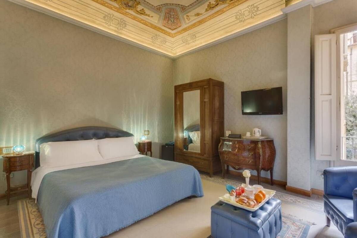 Une chambre d’hôtel avec un grand lit, une commode en bois, une télévision et une table à manger avec des articles pour le petit-déjeuner.