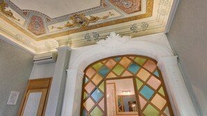 An ornate ceiling with intricate designs and a stained glass window with a diamond pattern.