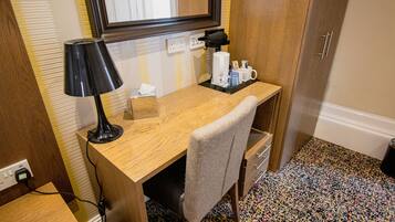 Un espacio de trabajo pequeño con un escritorio de madera, una lámpara, una silla y una máquina de café.