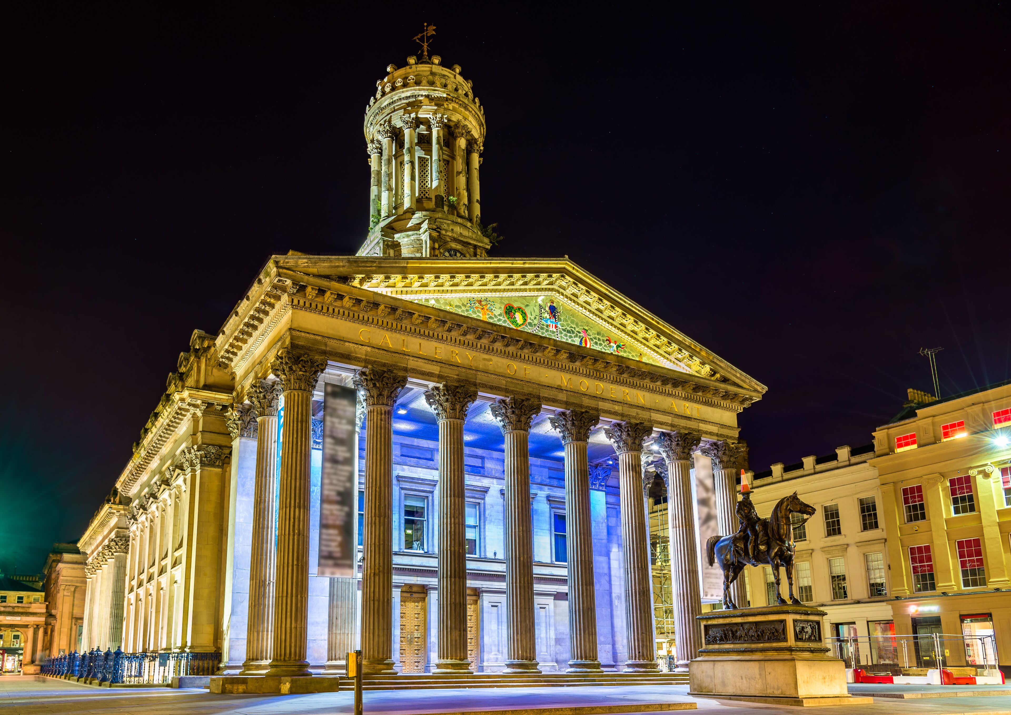 A classical building with a prominent dome and columns, illuminated at night.