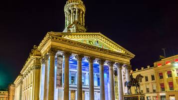 A classical building with a prominent dome and columns, illuminated at night.