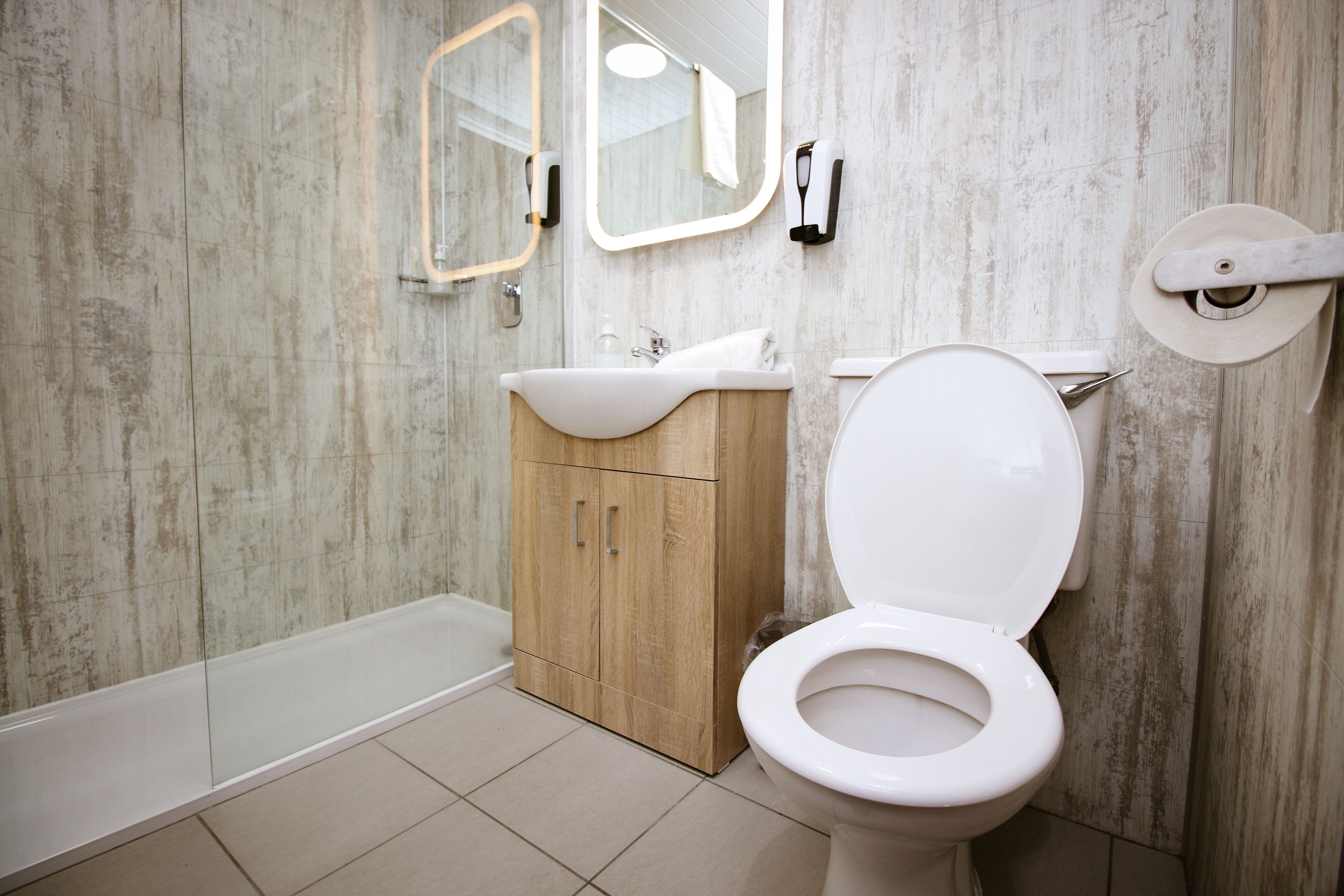 A bathroom with a white toilet, wooden cabinet, and a bathtub.