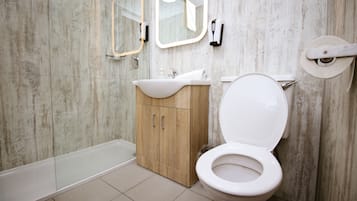 A bathroom with a white toilet, wooden cabinet, and a bathtub.