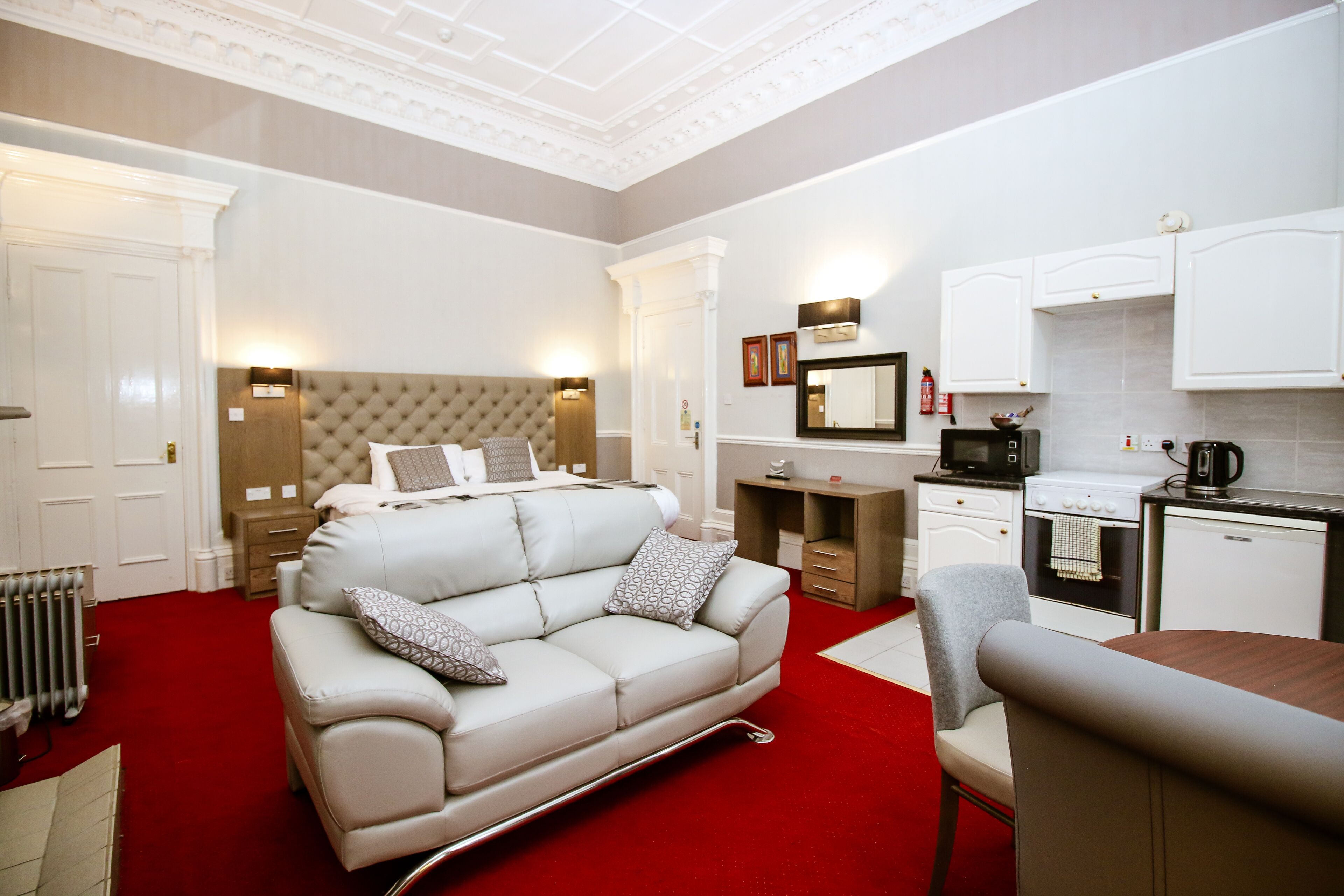 Una habitación de hotel con una cama grande, un sofá, una mesa de comedor y una kitchenette.