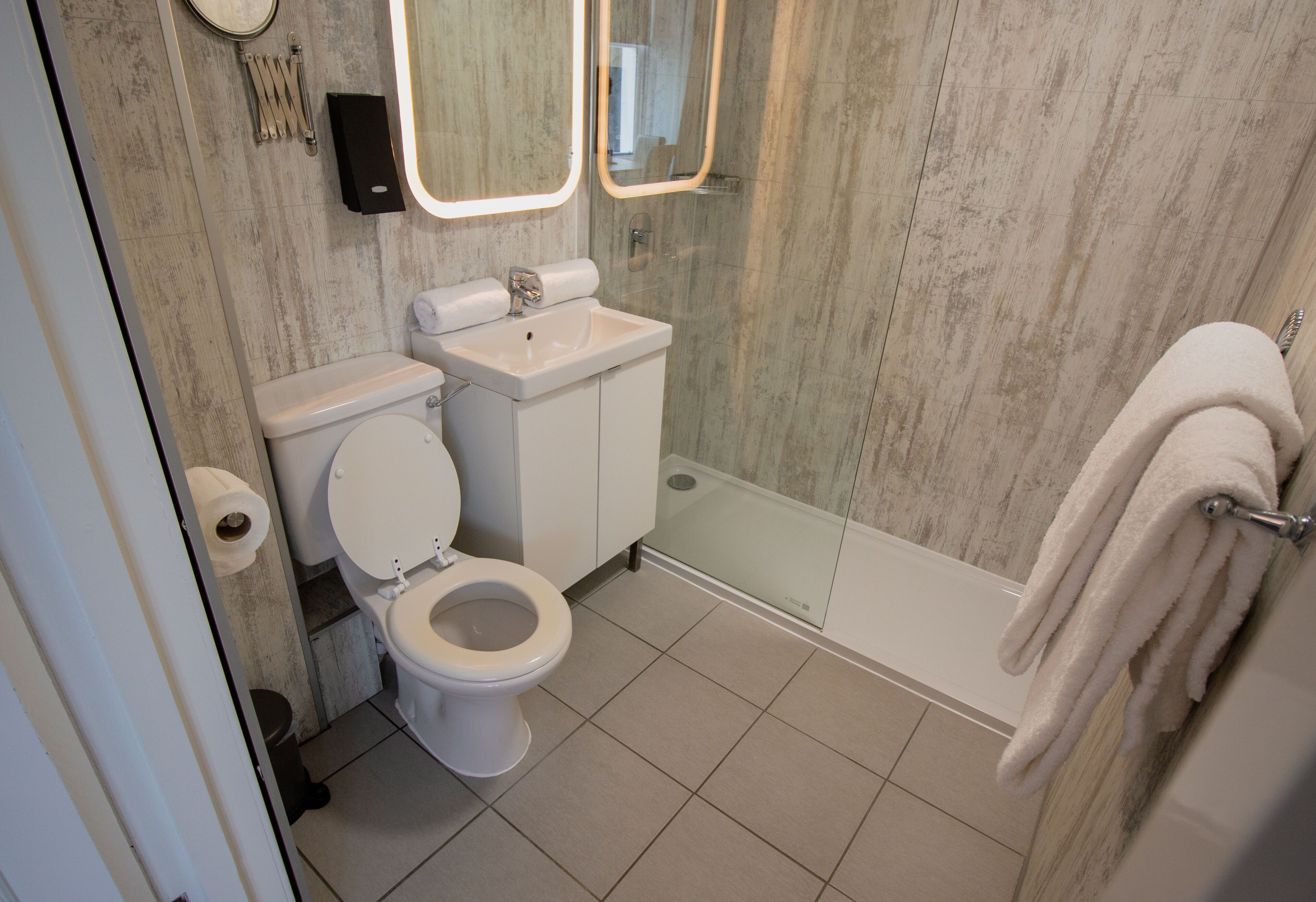 A bathroom with a toilet, sink, and glass shower enclosure.